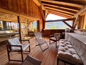 A wooden deck with seating, a table, and a view of the outdoors. - Semi-detached chalet with Giffre valley view (Samoëns)