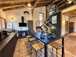 A modern kitchen with a central island, black bar stools, and a staircase leading to an upper level. - Semi-detached chalet with Giffre valley view (Samoëns)