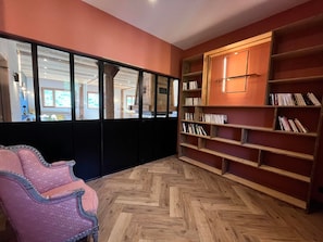 A room with a herringbone wooden floor, a pink upholstered chair, and a bookshelf filled with books. - Semi-detached chalet with Giffre valley view (Samoëns)