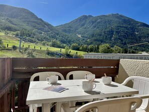 A table with white chairs and a bench, set against a backdrop of mountains and a clear sky. - Studio with slope view - 6 guests (La Salle-les-Alpes)
