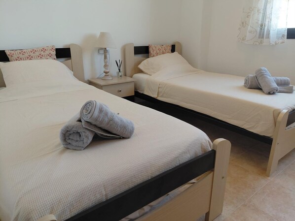 Ein Hotelzimmer mit zwei Betten, jeweils mit einem Kopfkissen und einem zusammengerollten Handtuch.