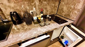Eine Küche mit Marmorarbeitsplatte, einer Kaffeemaschine, einer Weinflasche und einem Kühlschrank.