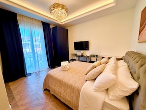 Habitación de hotel con una cama grande, televisor, escritorio y vistas por la ventana.