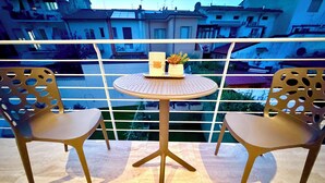 Ein Balkon mit zwei Stühlen und einem kleinen Tisch, mit Blick auf ein Wohngebiet.