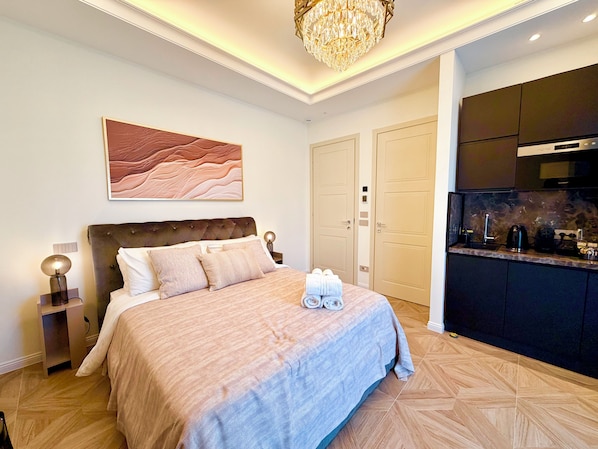 Un dormitorio con cama, mesita de noche, lámpara y un cuadro en la pared.
