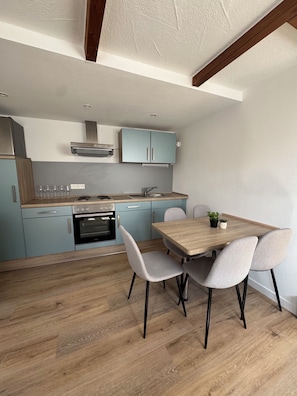 Une cuisine moderne avec des meubles de couleur bleu clair, un plan de travail en bois et un coin repas comprenant une table et des chaises.