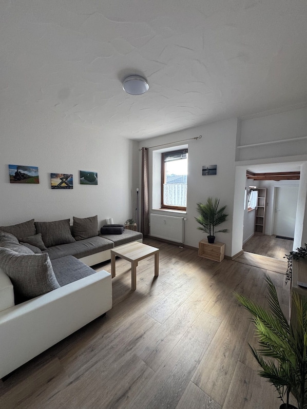 Una sala moderna con sofá, mesa de centro y ventana con cortinas.