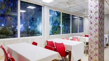 A dining area with tables and chairs, large windows with view, and a patterned column.