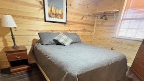 Una stanza con un letto, un comodino, una lampada e una finestra con persiane.