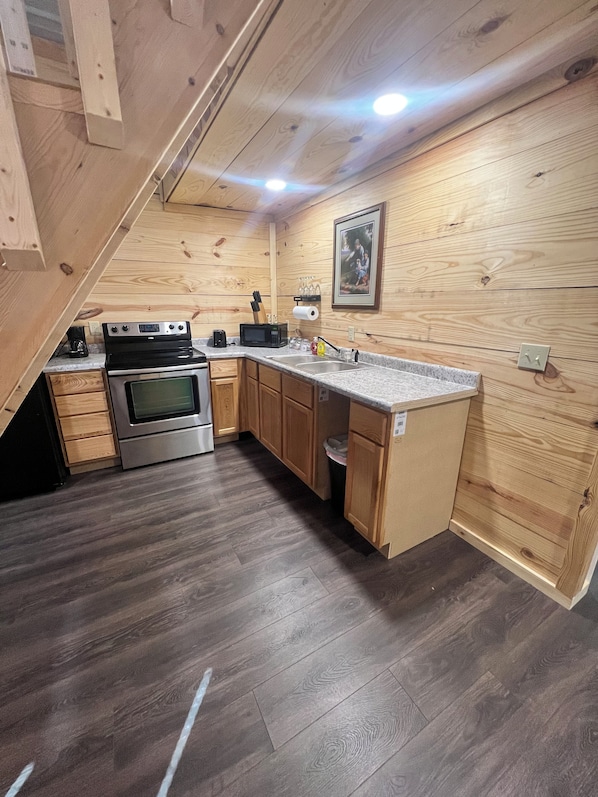 A compact kitchen with wooden cabinets, a stainless steel stove, and a granite countertop.