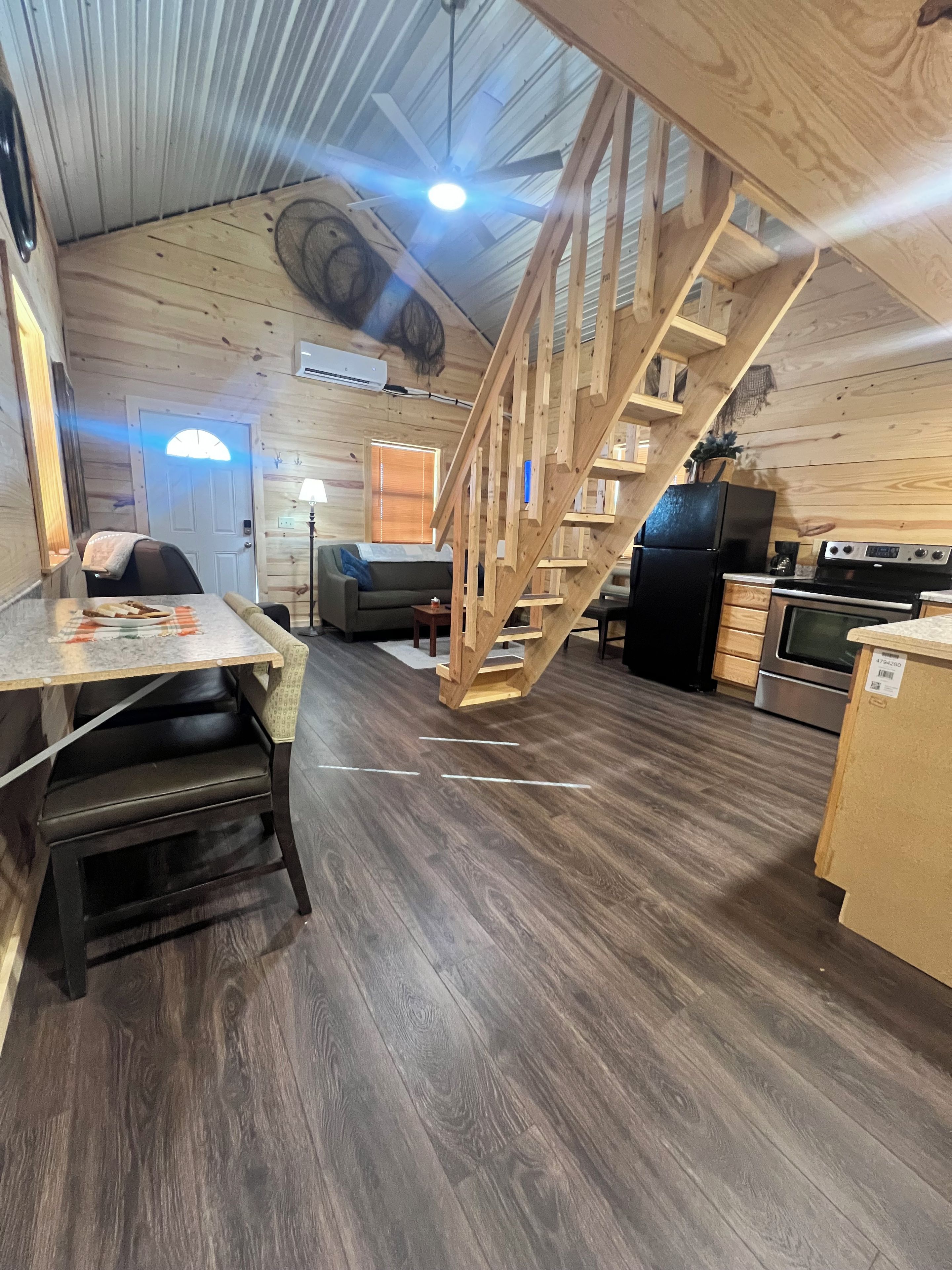 A wooden interior with a staircase, kitchen area, and seating space.