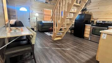 A wooden interior with a staircase, kitchen area, and seating space.
