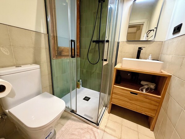 Ein Badezimmer mit Toilette, einer Duschkabine und einem Holzausleger mit Waschbecken.