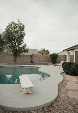 A swimming pool with a built-in bench, surrounded by a brick wall and a small garden area. - 4 Bedroom house with pool, putting green, and chef's kitchen! (Glendale)