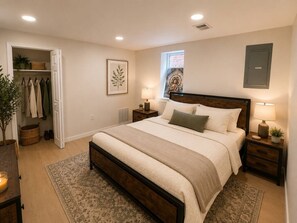 A bedroom with a large bed, bedside tables, a wardrobe, a window, and a wall-mounted cabinet. - Spacious & Stylish Retreat in Northeast DC (Washington)