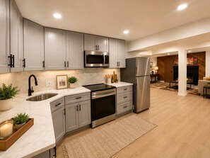 A modern kitchen with grey cabinets, stainless steel appliances, and a marble countertop. - Spacious & Stylish Retreat in Northeast DC (Washington)