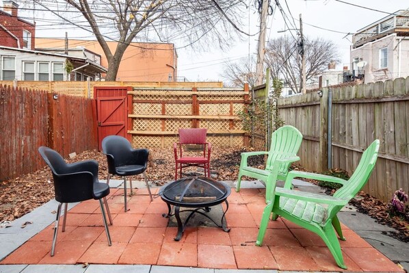 A patio with four chairs and a fire pit.