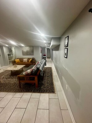 A spacious living area with a sofa, a bench, and a patterned rug.