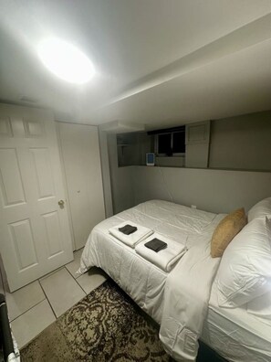 Een slaapkamer met een bed, nachtkastje, spiegel en een deur.