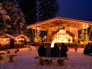 A snow-covered outdoor area with a wooden stage and benches, likely a venue for events or gatherings. - Heart of the Ahornblick House (Brandberg)