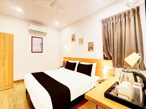 A hotel room with a bed, a desk with a lamp, a coffee maker, and a wall-mounted air conditioner. - Townhouse Casa Grand Himayatnagar (Hyderabad)