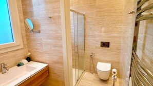 Ein modernes Badezimmer mit einem großen Spiegel, einem Waschbecken, einer Toilette und einer Duschkabine.