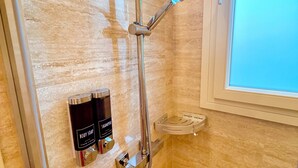 Ein Badezimmer mit Dusche, einem Fenster und zwei Körperwaschmitteln.