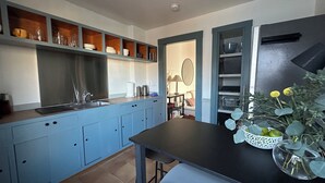 Eine moderne Küche mit blauen Schränken, einer schwarzen Arbeitsplatte und einem Essbereich mit Tisch und Stühlen.