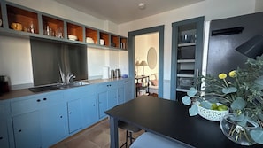 Una cocina moderna con armarios azules, encimera negra y un comedor con mesa y sillas.