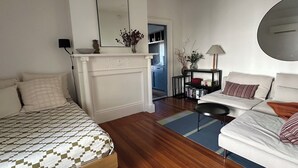 Ein Schlafzimmer mit einem Bett, einem Sofa, einem Kamin, einem Spiegel und einem Bücherregal.
