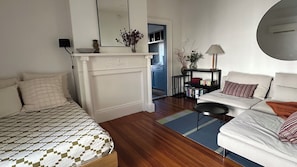 Un dormitorio con cama, sofá, chimenea, espejo y estantería.