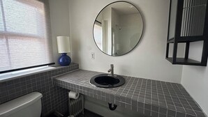 Ein Badezimmer mit Toilette, Waschbecken, Spiegel und einem Fenster mit Jalousien.