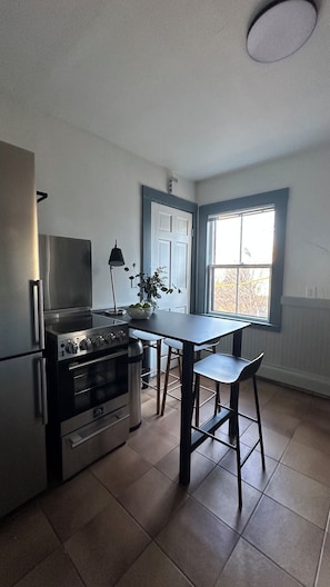 Una cocina con estufa, refrigerador y ventana.