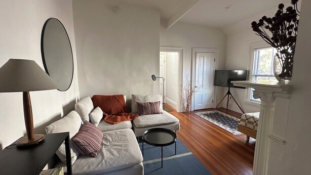 Ein Wohnzimmer mit einer Couch, einer Lampe, einem Fernseher auf einem Schrank und einem Kamin.