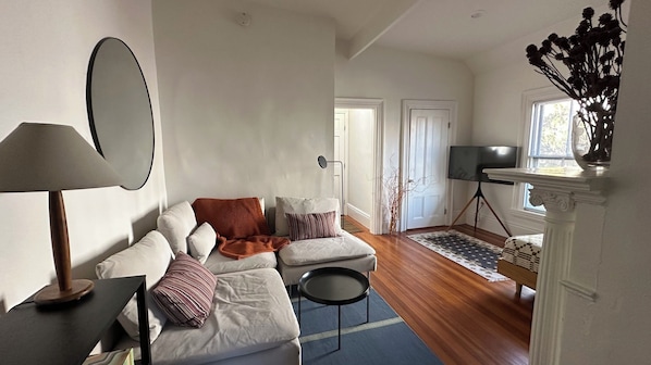 Una sala de estar con sofá, lámpara, televisor sobre un mueble bajo y chimenea.