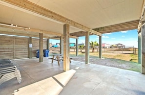 An outdoor covered area with picnic tables and benches, wooden beams, and a view of a residential area. - Beach House 3Bed/2Bath with Ocean View & Golf Cart (Surfside Beach)