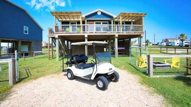 Een gebouw met twee verdiepingen, een overdekte patio en een golfkar voor de deur.