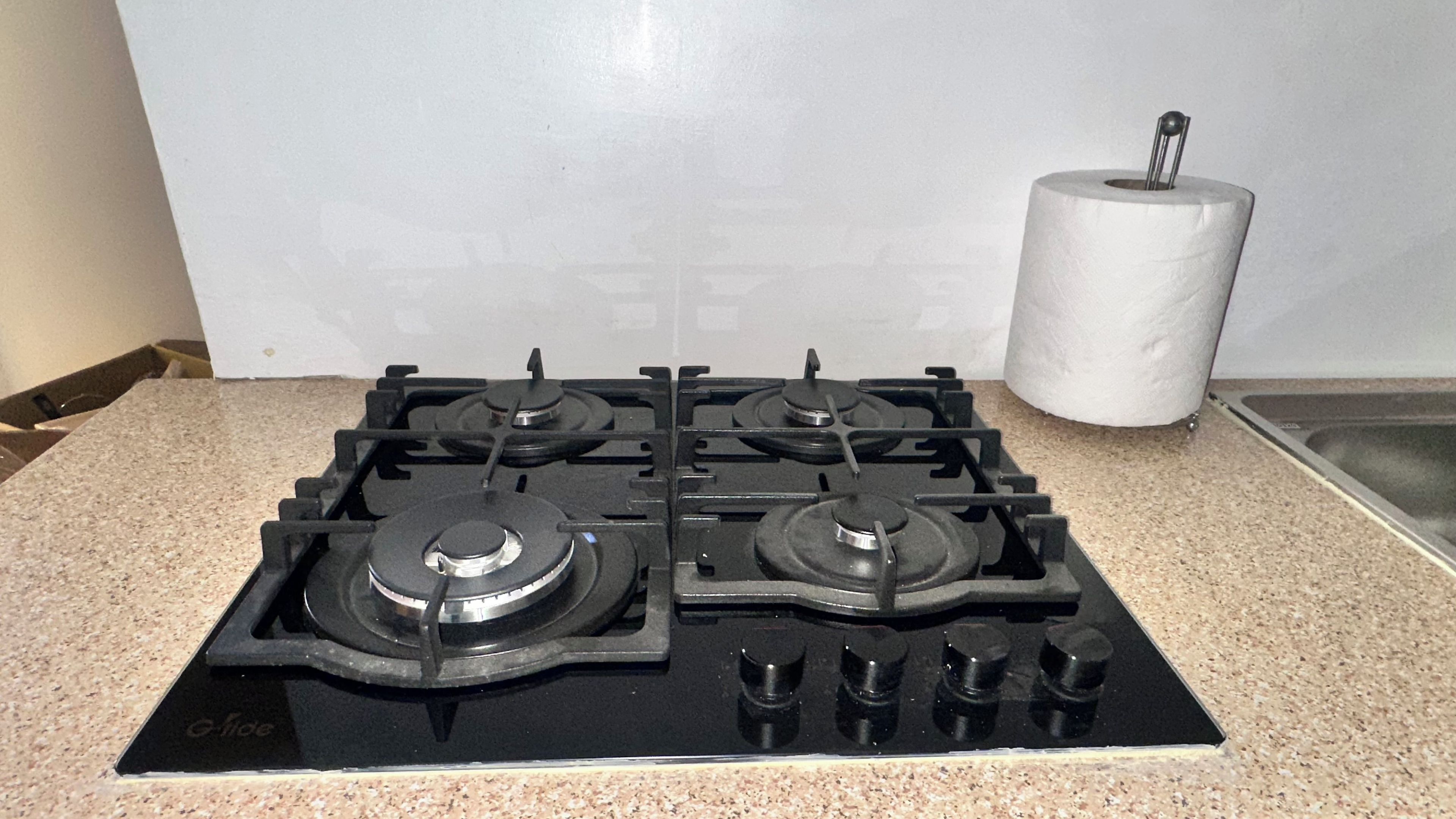 Una cocina con estufa a gas, dispensador de toallas de papel y un lavabo.