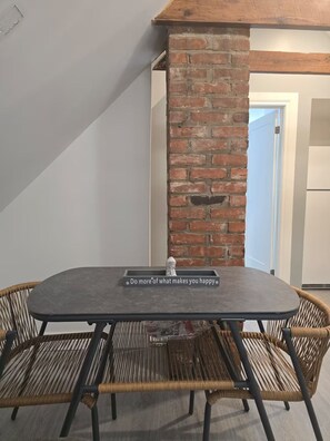 Un coin repas agrémenté d’un pilier en briques, d’une table ornée d’une citation inspirante et de chaises en osier.