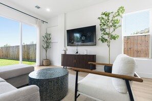 A modern living room with a flat-screen TV, a round coffee table, and a sofa. - 3-bedroom house with AC in Houston neighborhood (Houston)