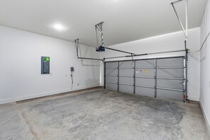 Eine Garage mit Betonboden, geschlossenem Garagentor und einem an der Decke befestigten Projektor.