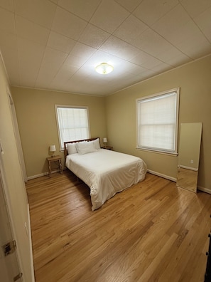 Un dormitorio con una cama, dos mesitas de noche y una ventana con persianas.