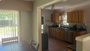 A kitchen with wooden cabinets, a countertop, and a dining area with a table and chairs. - Waterbury Home (Des Moines)