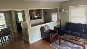 A living room with a sofa, a coffee table, a fireplace, and a view into the kitchen. - Waterbury Home (Des Moines)