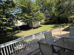 Eine Terrasse mit Gartenmöbeln, ein Rasen und ein Haus im Hintergrund.