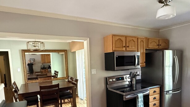 A modern kitchen with wooden cabinets, a stainless steel refrigerator, an oven, and a microwave. - Waterbury Home (Des Moines)
