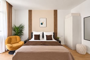 A modern bedroom with a bed, a chair, a plant, and a wardrobe. - Old Town & Kazimierz Apartments  (Kraków)