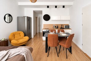 Una cocina moderna con armarios blancos, una mesa de comedor para cuatro personas y un refrigerador compacto.