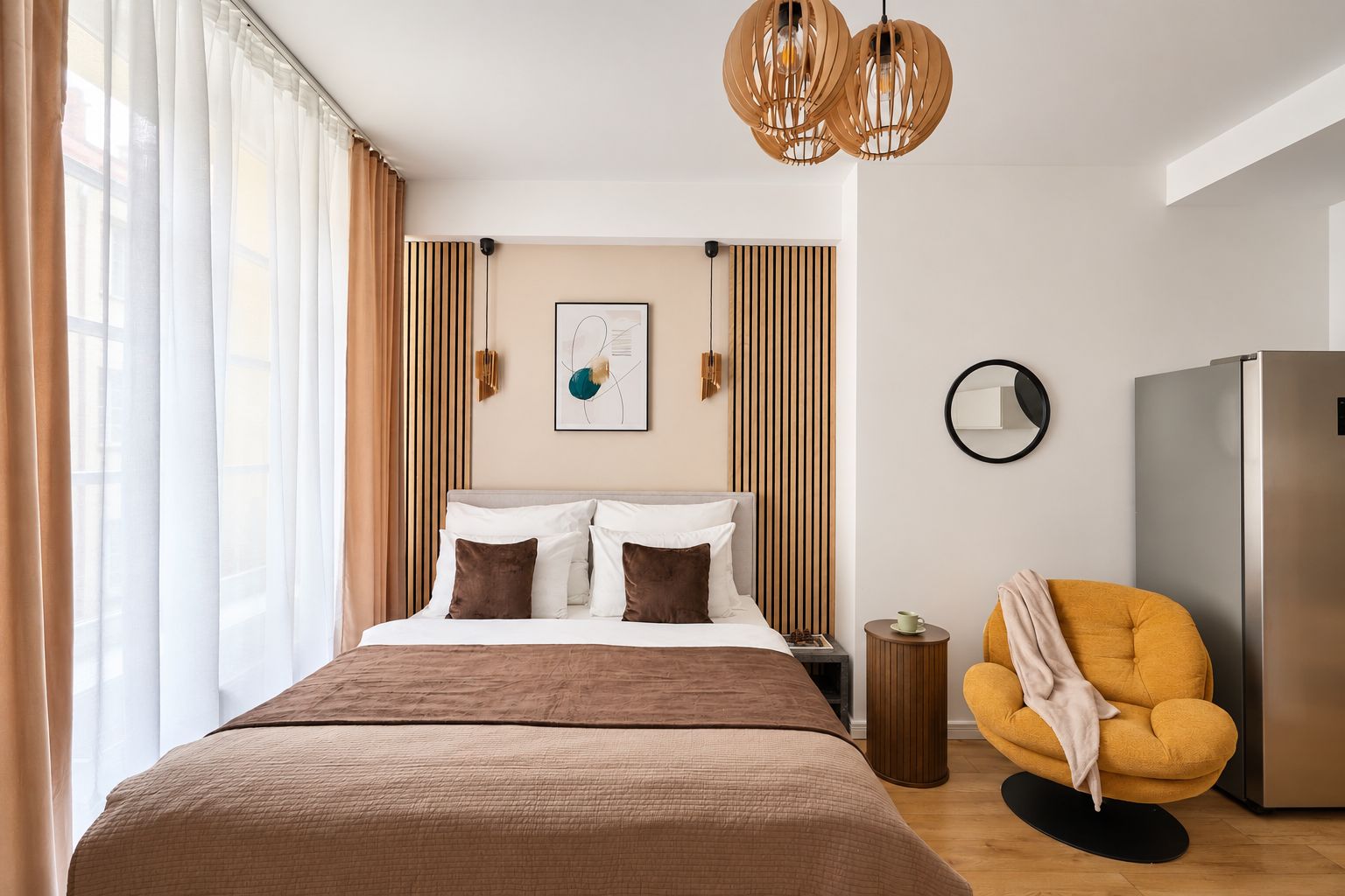 Una habitación de hotel moderna con una cama grande, un sofá, un refrigerador y una mesa de comedor.