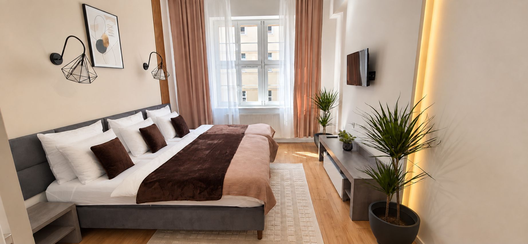 Un dormitorio moderno con una cama, mesitas de noche, un televisor y un ventanal con cortinas.